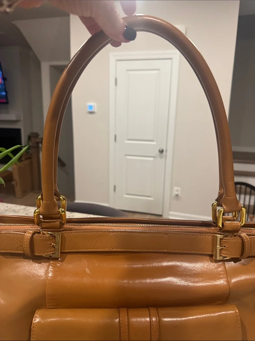 The Find Classic Tan Leather Weekender Travel Bag with Gold Hardware Buckle.